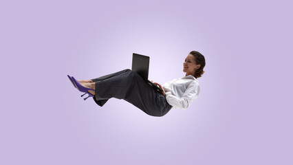 Business woman levitating with laptop on soft pastel background. Concept of easy work, remote...