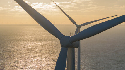 Aerial view of towering wind turbines stand as silent giants, harnessing the sea's energy against a backdrop of shimmering waves, Breezanddijk, Friesland, Netherlands. © Amazing Aerial