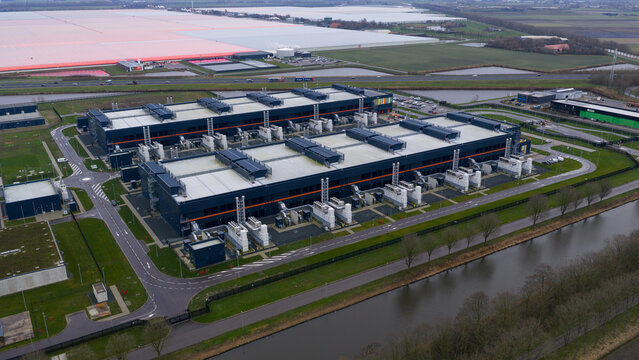 Aerial view of a vast data center complex surrounded by canals and greenhouses, Agriport, Middenmeer, Netherlands.