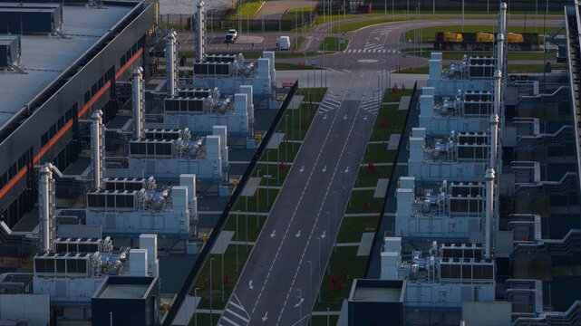 Aerial view of symmetrical rows of cooling units reflecting the soft light, contrasting with the dark building exteriors, Agriport, Middenmeer, Netherlands.