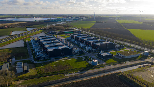 Aerial view of the expansive Data Center Agriport complex with its dark structures contrasting against the patchwork of green and brown fields, Middenmeer, Netherlands.
