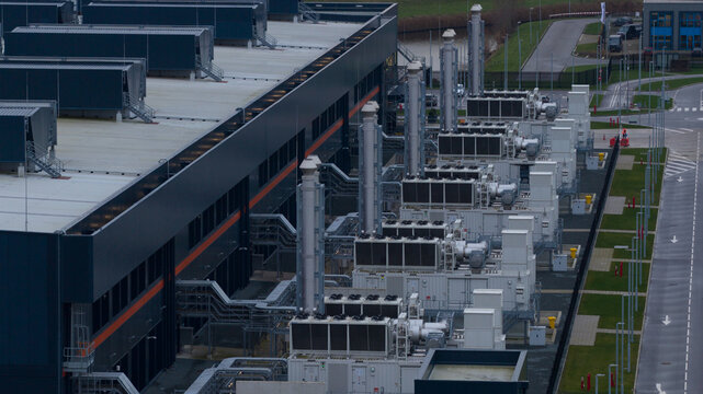 Aerial view of a modern data center's cooling infrastructure juxtaposes dark metal against the pale sky, Agriport, Middenmeer, Netherlands.