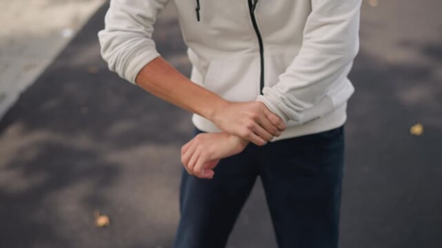 angry man clenching fists on asphalt, hoodie with rolled sleeves, tense torso and closeup hands, scattered leaves on wet pavement, moody overcast light, cinematic tension and confrontation energy