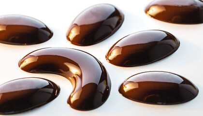 Close up of glossy brown gel capsules on white background.