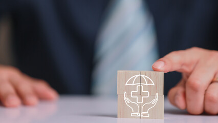 Businessman hand arranging wooden block with health insurance icon representing protection safety...