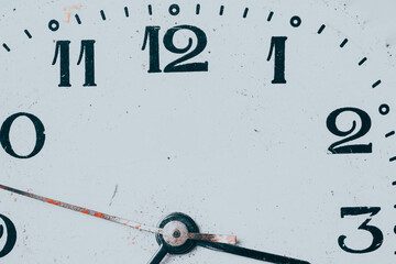 Vintage clock face close-up with worn numbers, scratched surface, and classic time concept background.