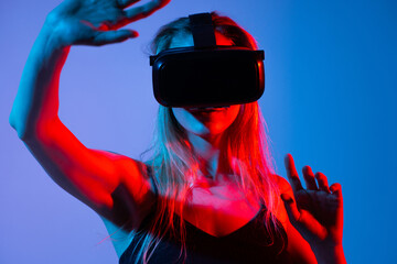 Close-up of woman in VR headset using hand gestures, virtual interface control with neon red blue lighting and immersive tech