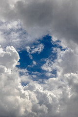 Obraz premium Dramatic weather concept. A gap in dense white clouds revealing the blue sky.