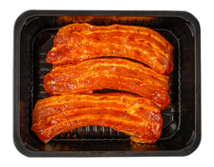 Top view of raw pork ribs coated in spicy marinade arranged in black plastic tray, fresh meat preparation and retail packaging concept isolated 