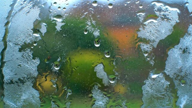 Frost melting on window glass time lapse. Ice patterns turning into water droplets close up.