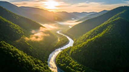 Golden light illuminates a majestic winding river as it gracefully carves through a vibrant green mountain valley, with ethereal mist clinging to the distant forested slopes at sunrise