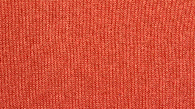 Close-up orange knitted texture background. Orange knitted sweater made of cotton, acryl, and nylon blended yarn.