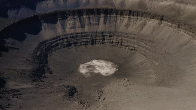 Drone flight over a massive meteor crater revealing layered geological structures from an impact, 8K.