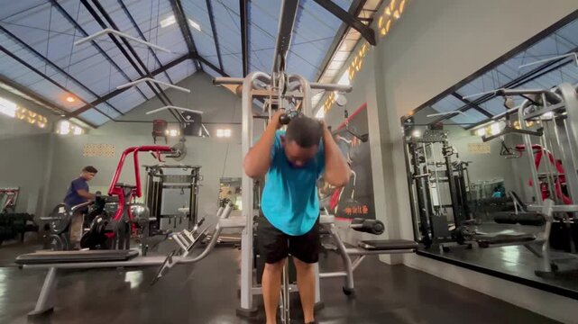 Side View of Middle-Aged Man Doing Cable Ab Crunches in Modern Gym