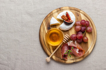 Fototapeta premium Appetizer board with meat, cheese, grapes, nuts, honey and fresh figs.