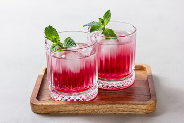 Raspberry cocktail with ice in a glass on a light background