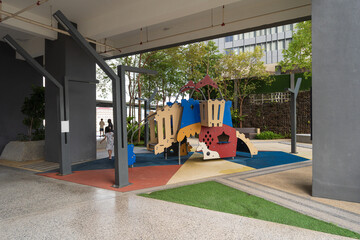 Modern colorful children's playground equipment located in a covered outdoor common area of a contemporary residential building