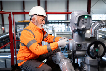Senior engineer checking industrial valves at refinery