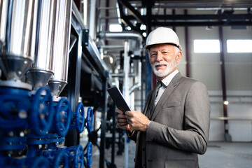 Senior ceo inspecting industrial plant with tablet