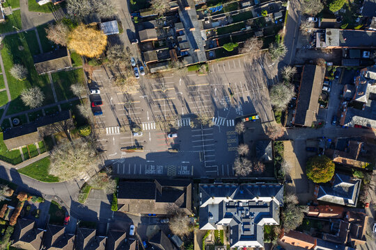 Aerial view of geometric parking lot patterns casting long shadows amidst the rooftops of Hartley Wintney, a serene scene, Hartley Wintney, England, United Kingdom.
