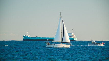 Fototapeta premium Sailboat, Motorboat, and Cargo Ship on Open Sea