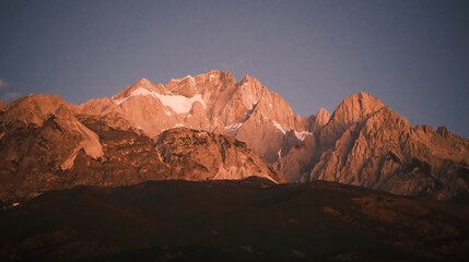 Naklejka premium Sunrise Glow on Jade Dragon Snow Mountain over Lijiang Old Town, Yunnan, China.
