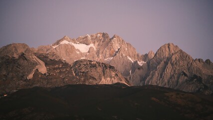 Sunrise Glow on Jade Dragon Snow Mountain over Lijiang Old Town, Yunnan, China.