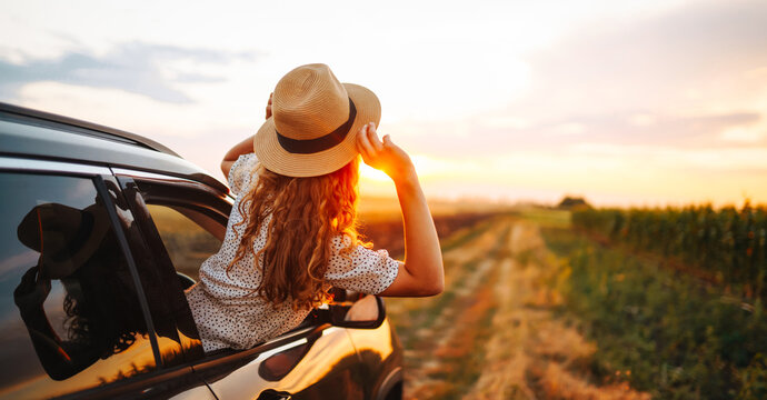 Young happy woman leaning out of the car window enjoying travel. The concept of active lifestyle