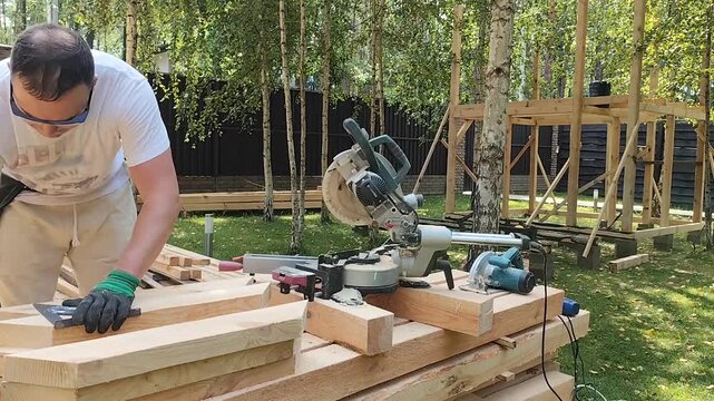 A male carpenter is building a house in the forest