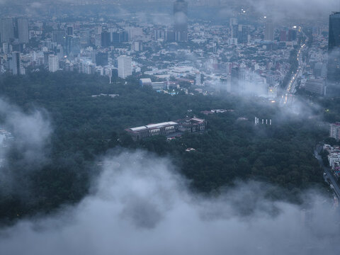 Aerial view of Chapultepec Castle shrouded in mist, contrasting with the distant city skyline, Mexico City, Mexico.