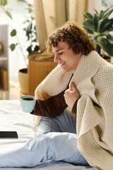 Relaxing moments of a curly teenager in his cozy apartment bedroom