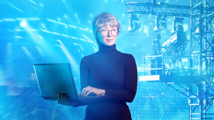 Event technology, lighting technician uses laptop to control stage lights and truss systems, supporting live show programming, visual effects and concert production.