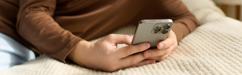 Teenage boy relaxing in stylish bedroom while using smartphone at home © LIGHTFIELD STUDIOS