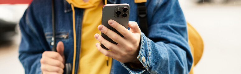A teen boy in casual wear enjoys autumn outdoors with a smartphone