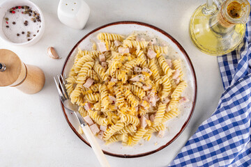 Tasty fussilli carbonara pasta with cheesy creamy sauce ham, topped with dried herbs and grated cheese