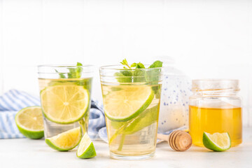 Hot mojito tea cocktail with rum, mint and lime slices, viral cold winter season warming motty - mojito version, with honey and ingredients on table background