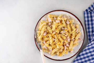 Tasty fussilli carbonara pasta with cheesy creamy sauce ham, topped with dried herbs and grated cheese