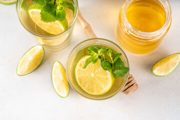 Hot mojito tea cocktail with rum, mint and lime slices, viral cold winter season warming motty - mojito version, with honey and ingredients on table background