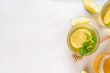 Hot mojito tea cocktail with rum, mint and lime slices, viral cold winter season warming motty - mojito version, with honey and ingredients on table background