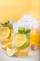 Hot mojito tea cocktail with rum, mint and lime slices, viral cold winter season warming motty - mojito version, with honey and ingredients on table background