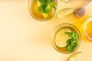 Hot mojito tea cocktail with rum, mint and lime slices, viral cold winter season warming motty - mojito version, with honey and ingredients on table background