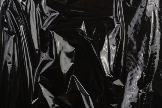 high-quality image of wrinkled black plastic film with expressive creases and highlights, creating an overlay effect and a modern transparent aesthetic