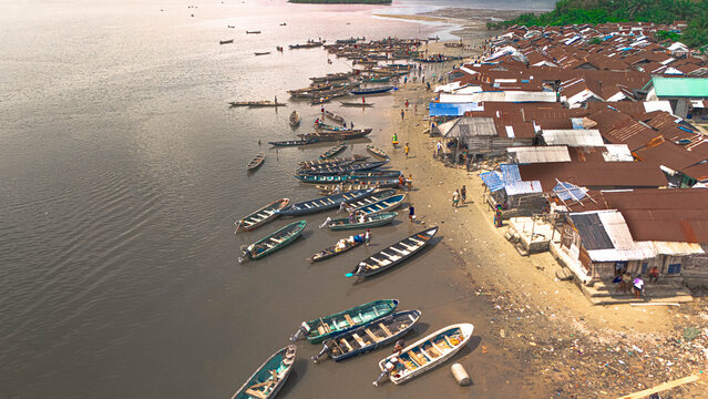 Aerial view of boats lining the shore near dwellings with corrugated roofs, a meeting of water and land, Kaa Waterfront, Khana, Bori, Nigeria.