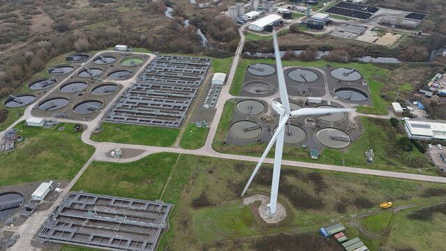 Aerial view of a stark landscape where a lone wind turbine stands tall amidst the wastewater treatment plant near West Service Road, Derby, England, United Kingdom.