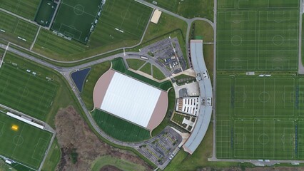 Aerial view of the curved building and the white roofed training facility surrounded by green football pitches, Sileby, England, United Kingdom.