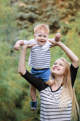 Mom and son outdoors in the summer. Mother is holding the kid boy in her arms and kissing him