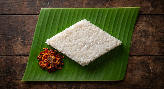 Traditional Sri Lankan Kiribath (milk rice), shaped in a diamond and served on a banana leaf with spicy Lunu Miris, symbolizing prosperity and heritage. This cultural dish is central to celebrations 