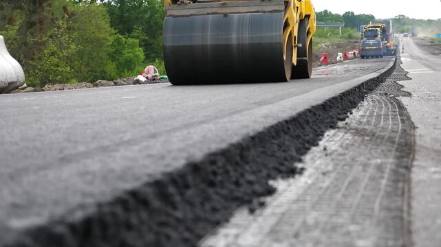 Roller laying new asphalt layer. Special machinery making road. Compactor constructing highway. Steamroller slowly ride. Roadway repair by heavy machinery. Concept of roadwork and motorway maintenance