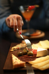 Gourmet charcuterie and tapas board featuring artisan cheeses, cured meats, olives, and savory tartlets. Elegant fine dining appetizer service in a luxury bar or lounge setting.