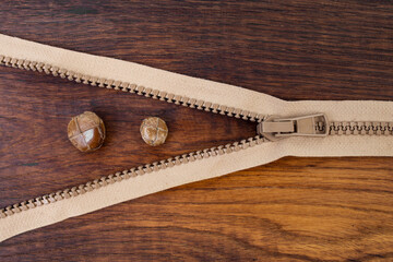 Vintage leather buttons and zipper on brown oak wood desk background, flat lay close up, abstract still life